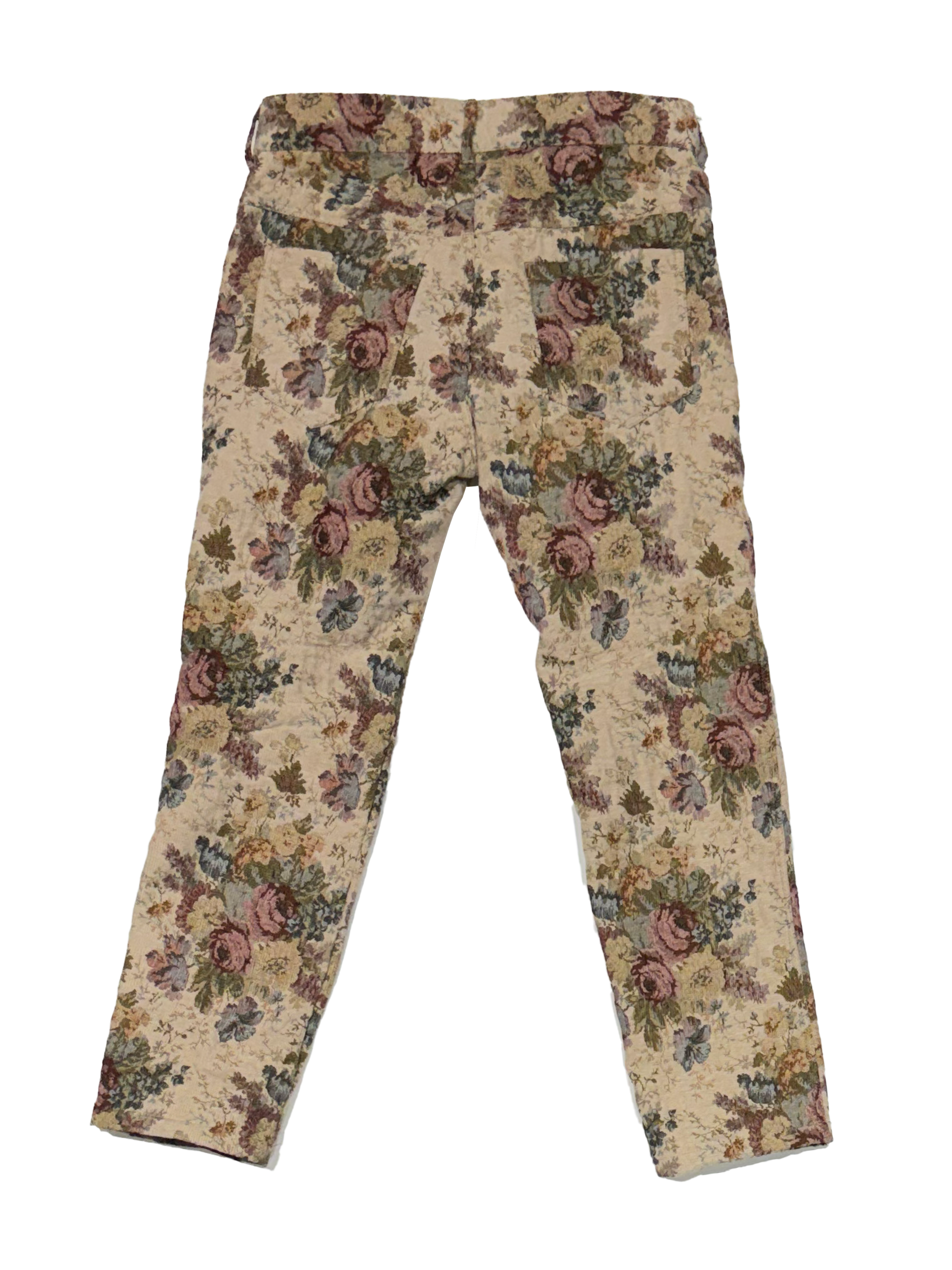 A pair of cropped pants featuring a vintage floral tapestry pattern in muted tones of pink, green, and brown on a beige background.
